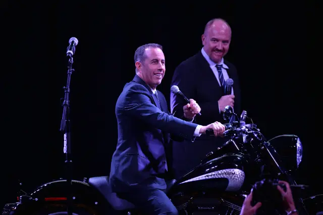 Jerry Seinfeld performing live, with unidentified man in background